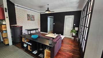 A modern kitchen with a dining area, featuring a brick wall, a black ceiling, and a large window.