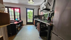 Una cucina con un lungo bancone, un frigorifero e una finestra che si affaccia sul verde.
