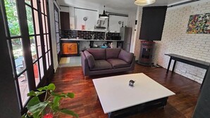 A modern kitchen with a dining area, a sofa, and a fireplace.