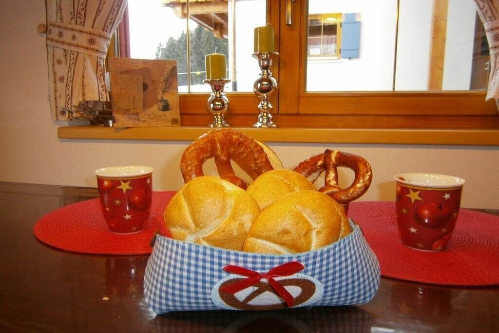 Ein Tisch mit einem Korb voller Brötchen, einem Brezel und zwei tassenförmigen Sternen.