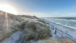 Une plage avec des dunes et l’océan.