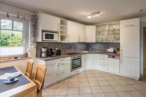 A modern kitchen with white cabinets, a microwave, a stove, and a coffee maker. - Holiday home in Prerow with swimming pool (Prerow)