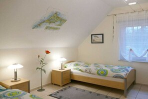 A bedroom with a single bed, a nightstand, a lamp, a small table, a map on the ceiling, and a window with curtains. - Holiday home in Prerow with swimming pool (Prerow)