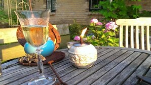 Ein Holztisch mit einem Glas Wasser, einer Kerze und einem kleinen Topf mit Blumen.