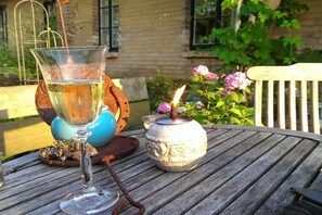 Una mesa de madera con un vaso de agua, una vela y una maceta con flores.