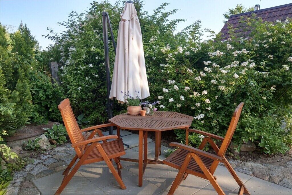 Une terrasse extérieure avec une table ronde en bois et quatre chaises en bois.