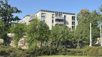 A multi-story building with a flat roof, surrounded by trees and greenery.