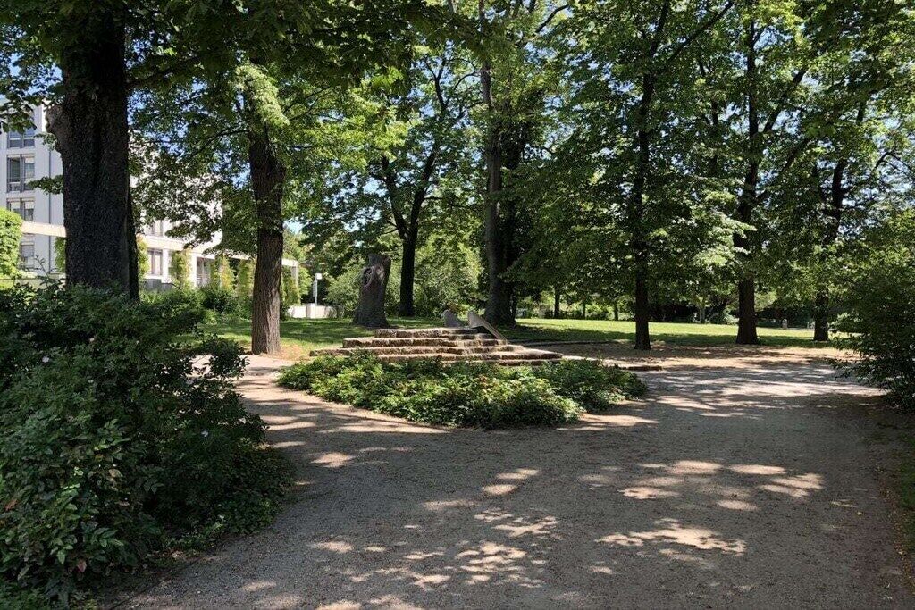 A park with a gravel path, trees, and a stone staircase.