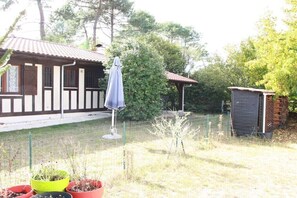 Ein Haus mit einer Veranda, einem umzäunten Garten und einem kleinen Geräteschuppen.