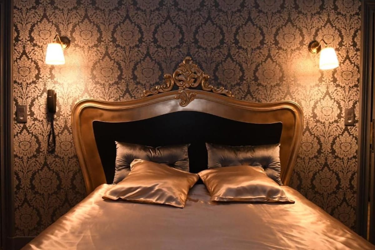 A bed with a dark headboard and two wall-mounted lamps on either side.
