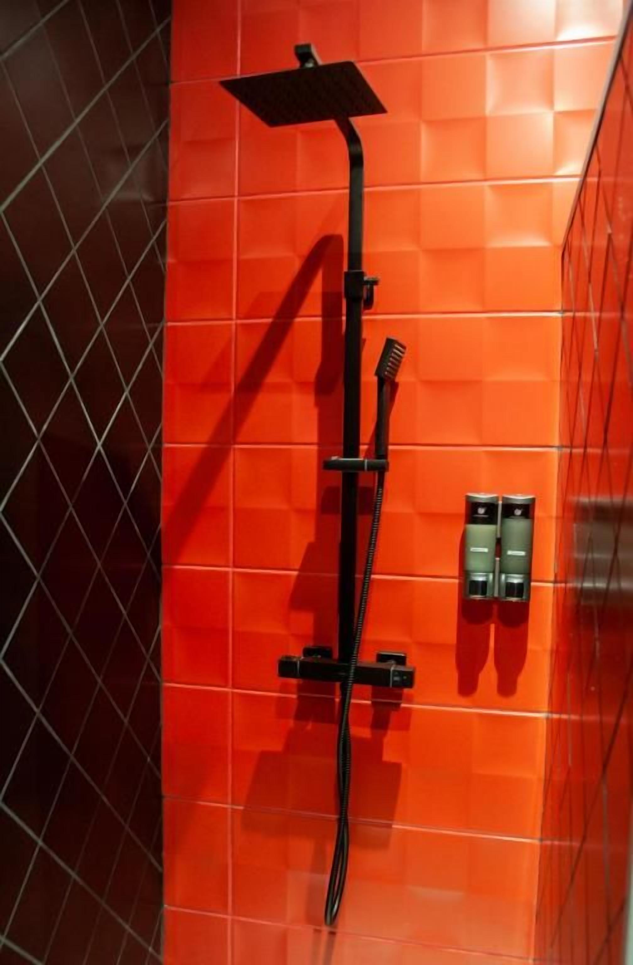 Eine Dusche mit Handbrause und Bedienfeld an der Wand.