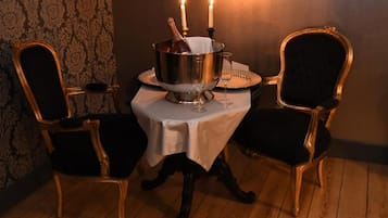 A dining table with a metal centerpiece, two chairs, and candles.