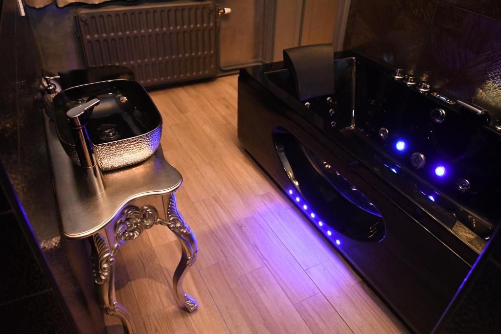 Una habitación con una mesa de masaje negra, una silla pequeña y un radiador al fondo.