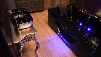Een kamer met een zwarte massagetafel, een kleine stoel en een radiator op de achtergrond.