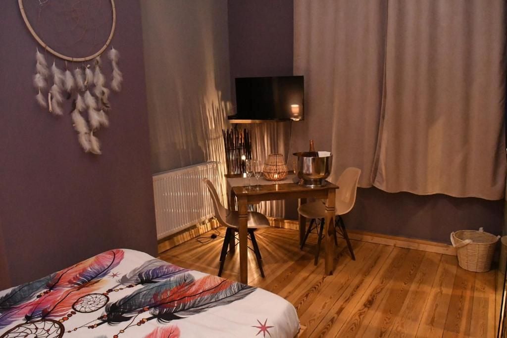 Una habitación con cama, escritorio, silla, televisor y radiador.