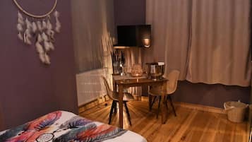 Een kamer met een bed, een bureau, een stoel, een televisietoestel en een radiator.