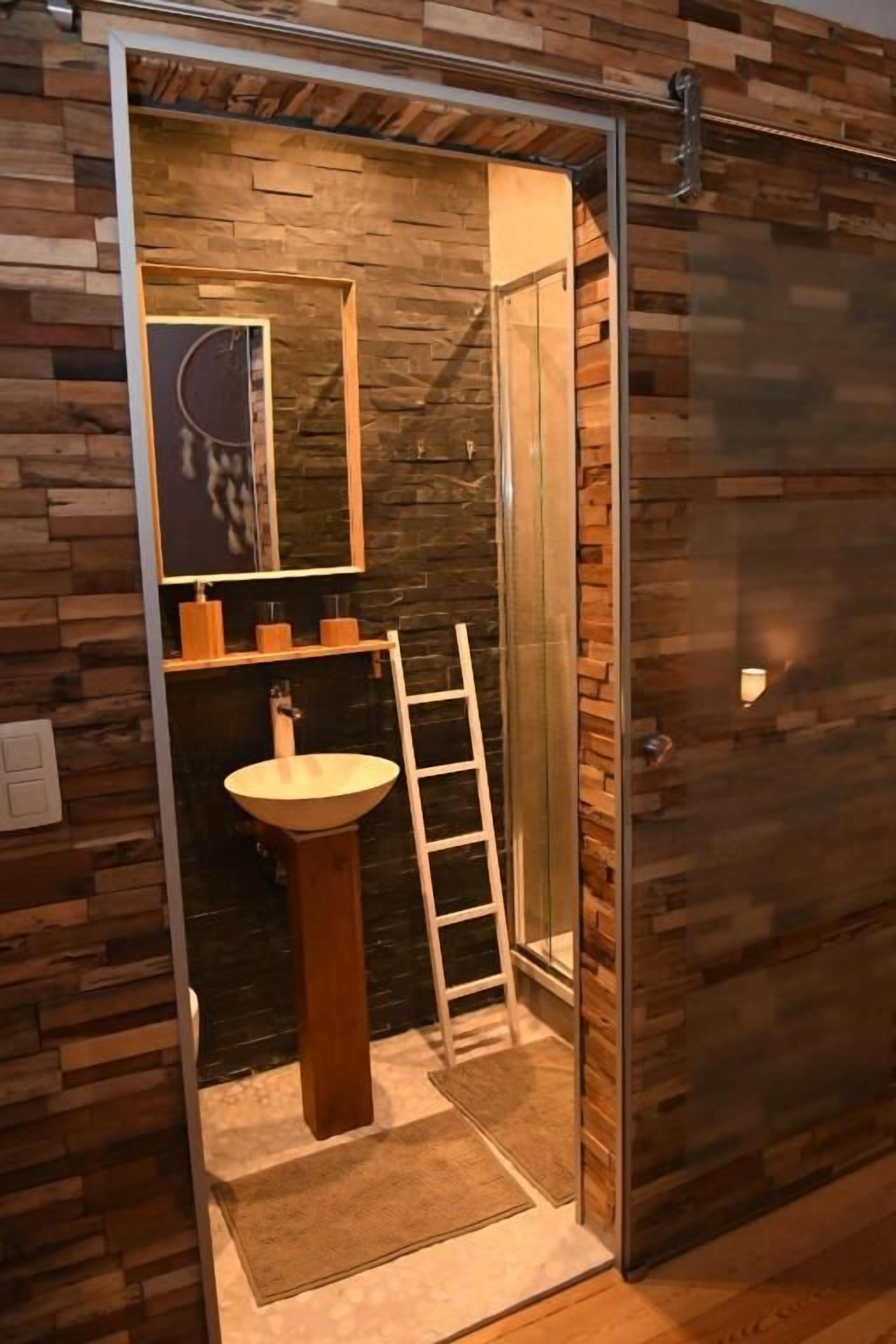 Une salle de bain avec un mur en bois, un lavabo et une échelle.