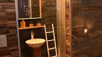 Une salle de bain avec un mur en bois, un lavabo et une échelle.