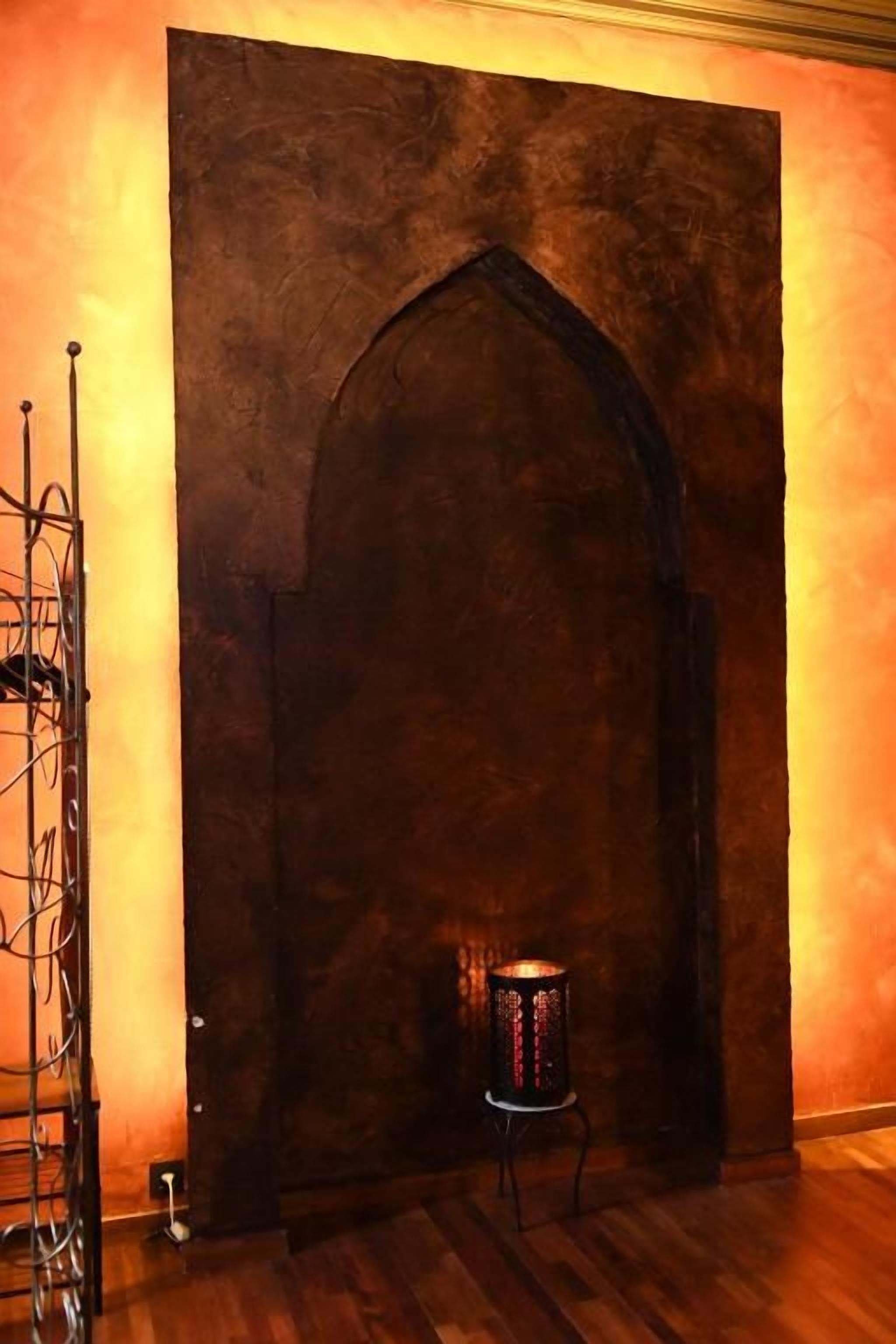 Una habitación con un amplio arco, un soporte metálico con cables y un objeto cilíndrico iluminado.