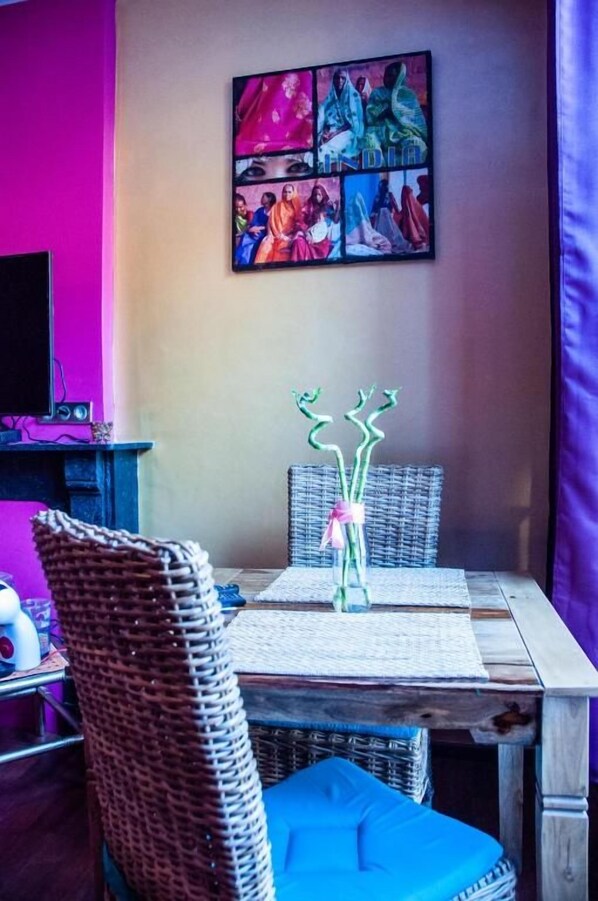 A dining area with wicker chairs, a table, and a wall-mounted artwork.