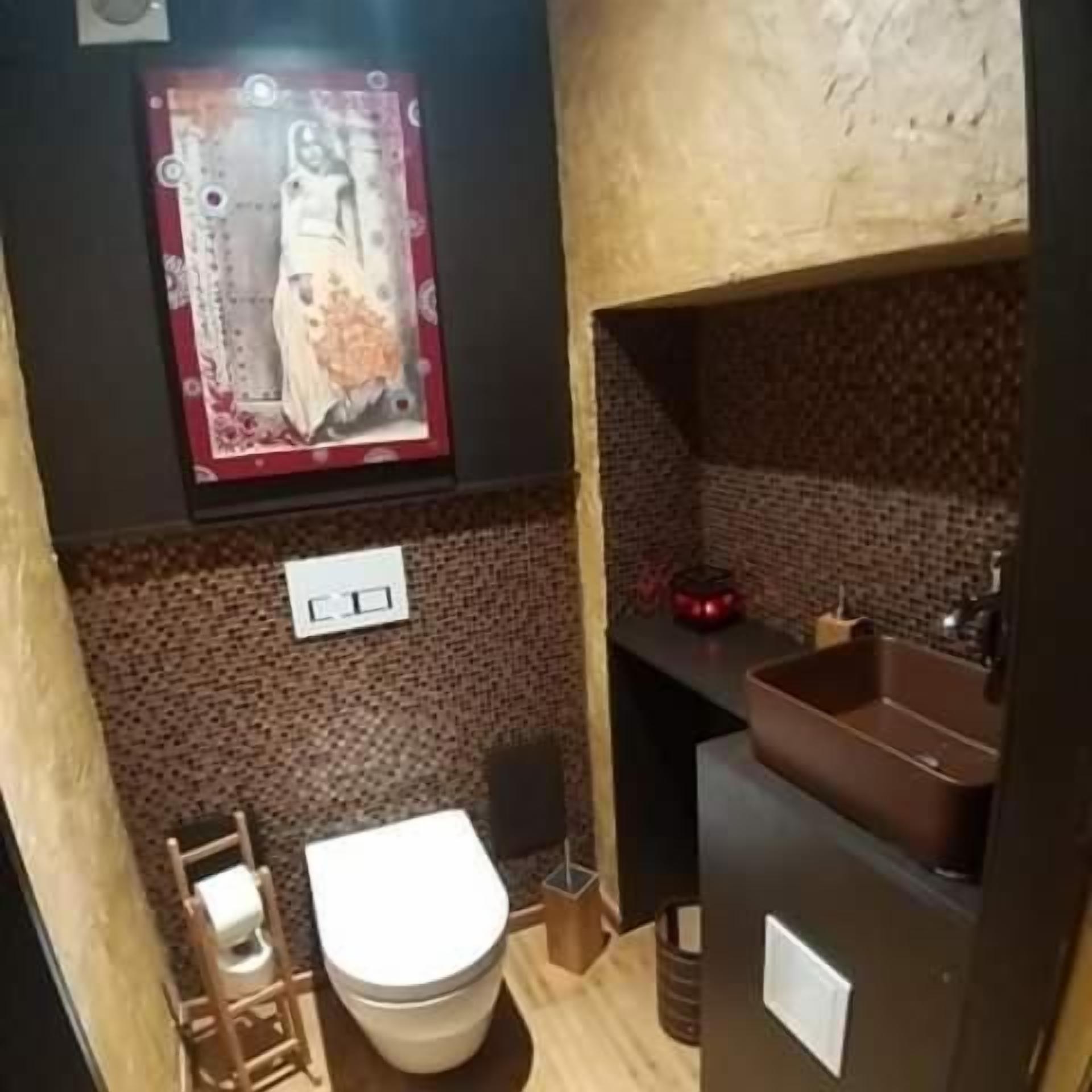 A bathroom with a toilet, sink, and decorative wall art.