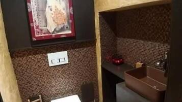 A bathroom with a toilet, sink, and decorative wall art.