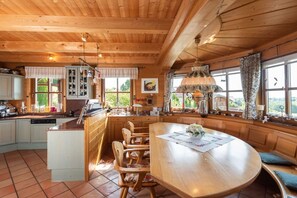 L’intérieur d’un chalet en bois comprend une cuisine, un coin repas et de grandes fenêtres.