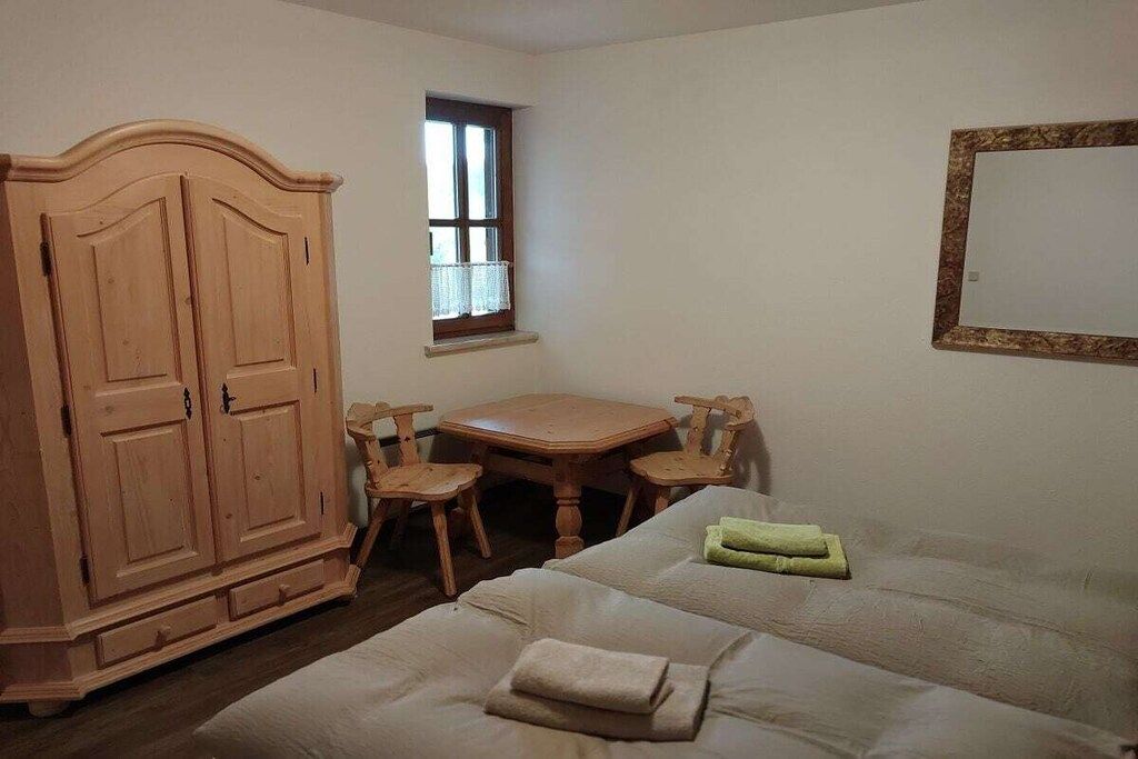 A room with a bed, a wooden wardrobe, a small table with chairs, and a window.