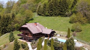 Een ruime houten chalet met balkon, omgeven door een gazon en bomen.