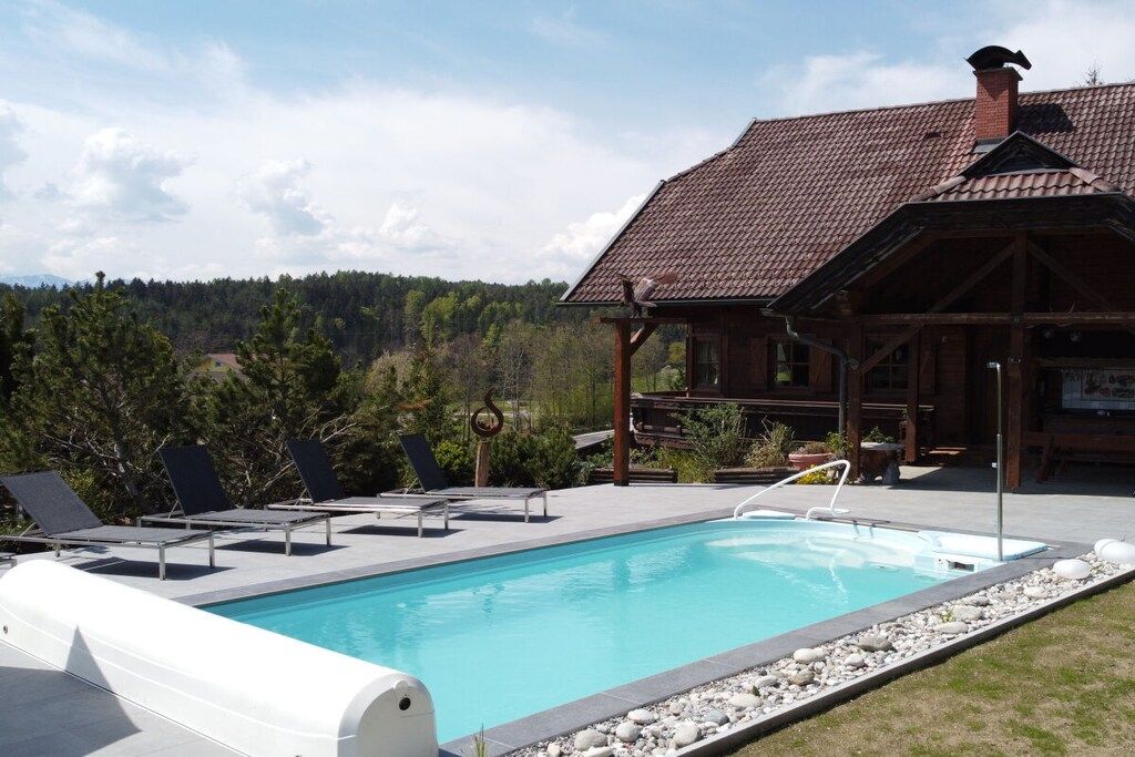 A pool area with lounge chairs and a wooden building in the background.