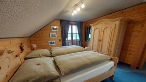 Een kamer met houten vloer, een bed, een kledingkast en een raam met gordijnen.