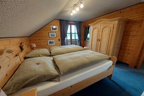A wooden room with a bed, a wardrobe, and a window with curtains. - Kraxlhütte Carinthia (Dröschitz)
