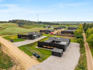 Ein moderner Gebäudekomplex mit mehreren Gebäuden, einer Schotterauffahrt und einem Feldweg.