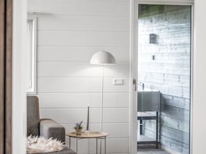 Une salle de bain moderne avec un mur recouvert de carreaux blancs, un lampadaire blanc, une petite table ronde avec une bougie et un banc gris.