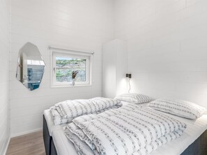 Ein Schlafzimmer mit einem Bett, einem Fenster mit Blick, einem wandmontierten Spiegel und einer Steckdose.