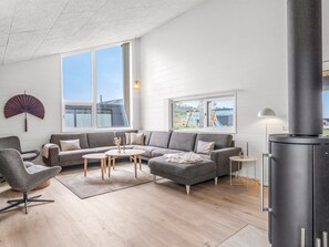 Moderni olohuone, jossa on harmaa sohva, pyöreä sohvapöytä ja musta takka.