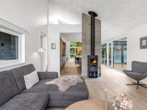 A modern living room with a grey sofa, a round wooden table, and a fireplace. - "Filippine" - 800m from the sea by Interhome (Glesborg)