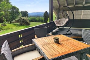 Een terras met rieten meubels, een hangstoel en een houten tafel met een plant.