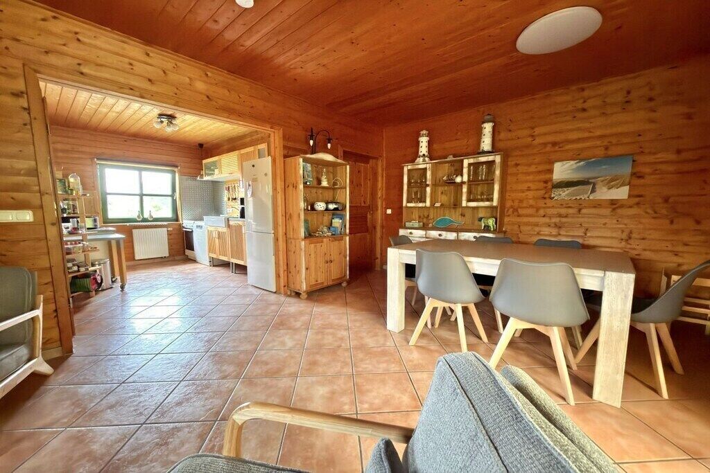 Un intérieur en bois comprenant un coin repas, une cuisine et une vue sur l’extérieur.
