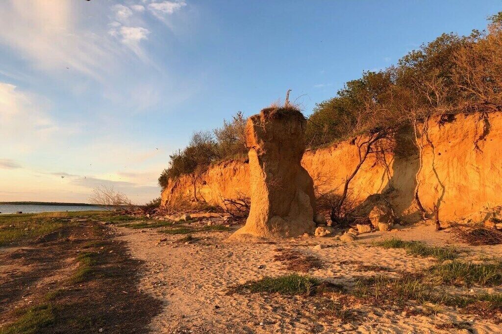 Een natuurlijk landschap met een zandpad dat naar een grote rotsformatie leidt.