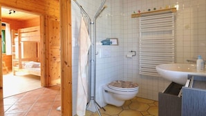 L’intérieur d’une cabane en bois comprend une salle de bain équipée de toilettes, d’un lavabo et d’une douche.