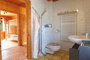 Het interieur van een houten chalet met een badkamer, inclusief toilet, wastafel en douche.