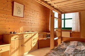 Ein Holzblockhaus-Interieur mit einem Bett, einem Schminktisch und einem Fenster.