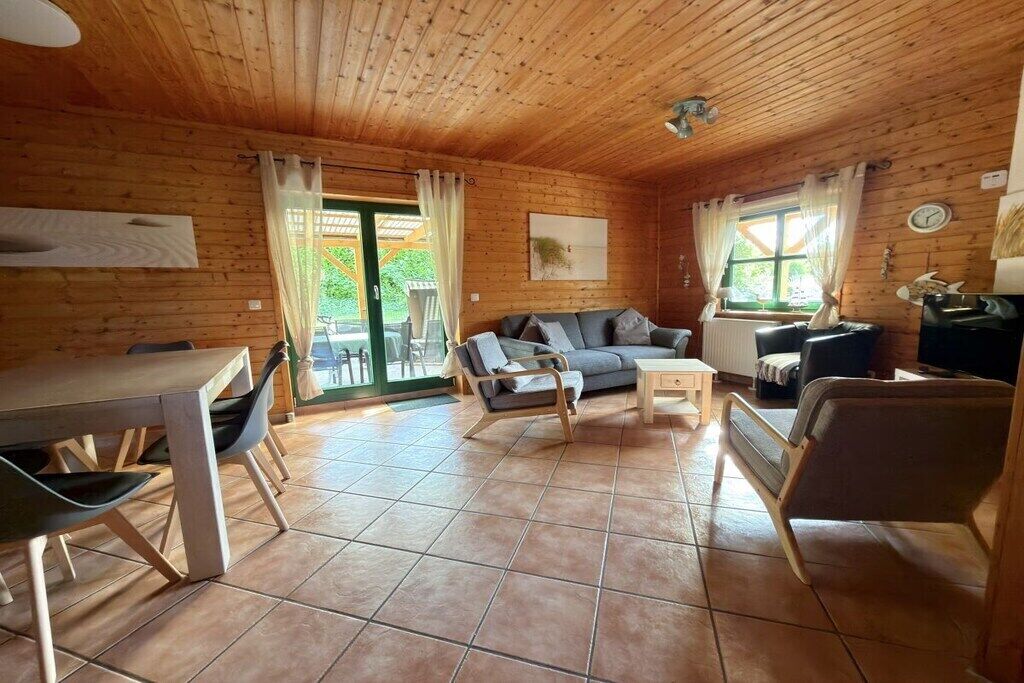 Interior d'una cabana de fusta amb zona de menjador, sofà i televisió.