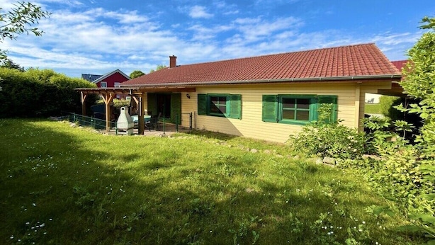 Un bâtiment d’un seul étage, avec un toit recouvert de tuiles rouges, un porche abrité et une pelouse bien entretenue.