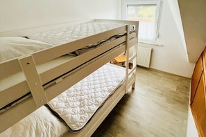 A bunk bed with a window above it, a radiator below, and a wooden floor. - "Little Friesian" Dangast (Varel Dangast)