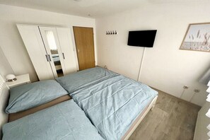 A bedroom with a bed, wardrobe, and a flat-screen TV mounted on the wall. - "Little Friesian" Dangast (Varel Dangast)