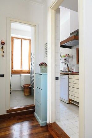 A narrow hallway leading to a kitchen with a refrigerator, a window, and a sink. - Garbatella: Apartment with a terrace near the metro (Roma)