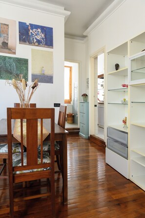 Ein Essbereich mit einem Holztisch und Stühlen, einem Bücherregal und Kunstwerken an den Wänden.