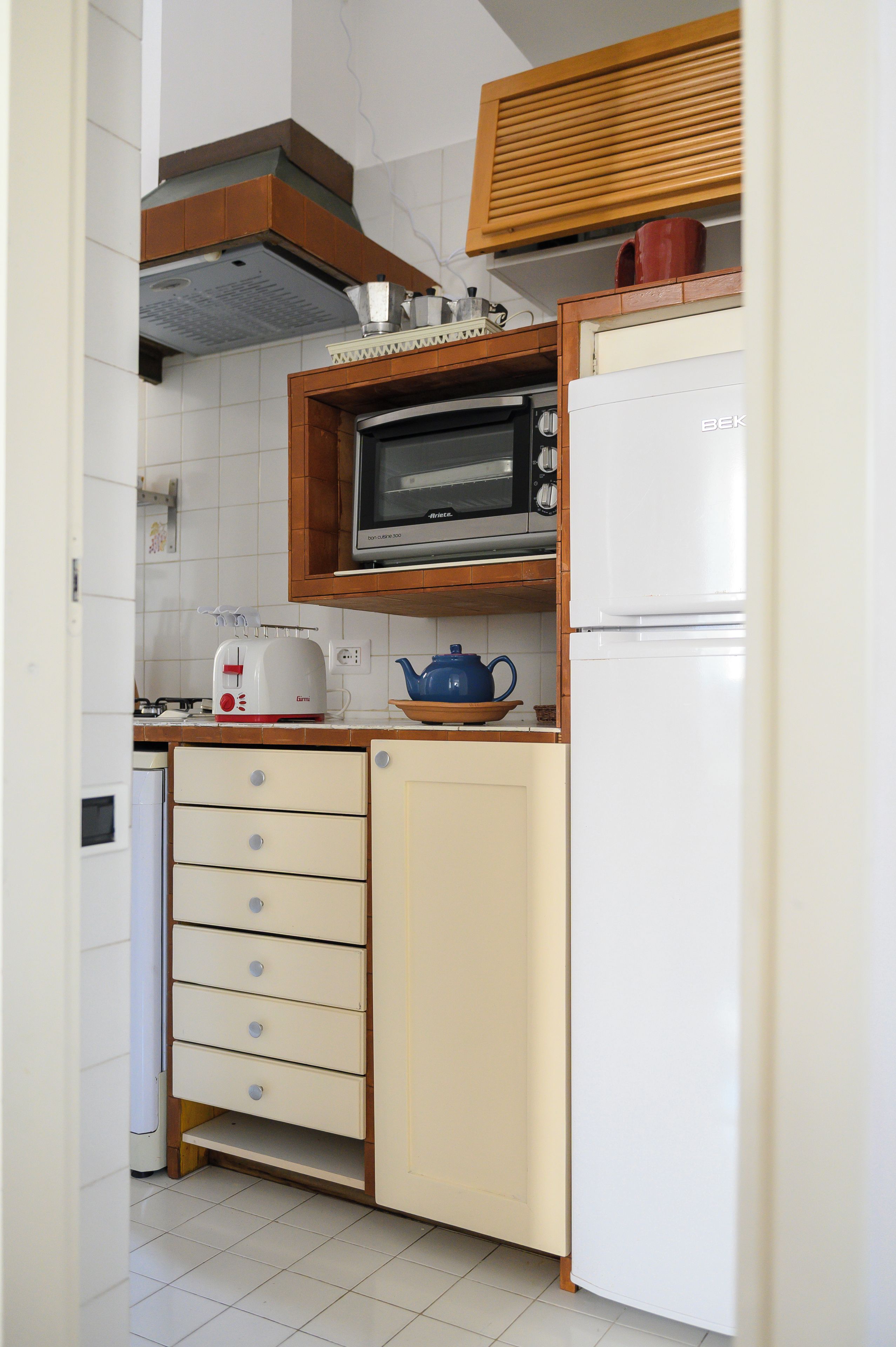 A compact kitchen with a built-in oven, microwave, and a refrigerator.